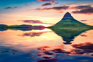 Kirkjufell peak reflected in the calm waters of Atlantic ocean. Majestic summer sunset in...