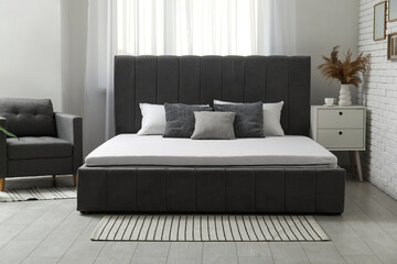 New orthopedic mattress on stylish bed in room