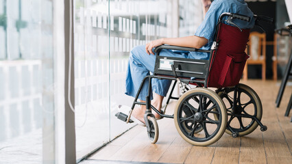 Fototapeta premium Individual in a wheelchair resting by a large window, creating a peaceful, reflective and inclusive atmosphere in a modern indoor setting.