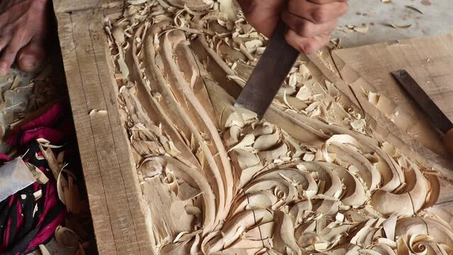 A carpenter makes floral artistic carving designs by hammer  in wooden furniture video. 4K.