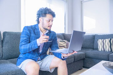 上半身だけスーツを着てオンライン会議に参加する男性