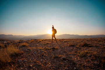 hiking in the mountains. a man with a backpack raises his hand up on a mountain against the...