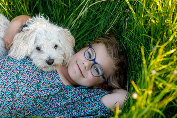 Adorable cute little girl and her puppy on the nature in the summer. Happy school child with...