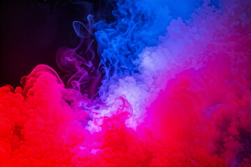 Fototapeta premium Dramatic smoke and fog in contrasting vivid red, blue, and purple colors. Vivid and intense abstract background or wallpaper.