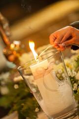 A closeup of a hand lighting a candle in a serene ceremony setting, creating a warm and peaceful atmosphere
