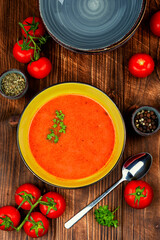 Bowl of tomato soup on a wooden table.