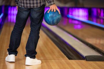 man throwing a ball to knock down the skittles
