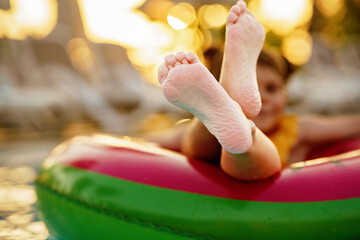 Happy little girl with inflatable toy ring float in swimming pool. Little preschool child learning...