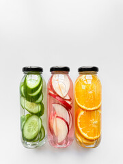 Variety detox drinks in glass bottles on white background, with copy space. Healthy lifestyle and hydration concept for design and print.
