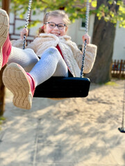 Adorable little girl having fun on a swing. Happy child on playground on sunny day