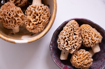 Bright image of two bowls of morel mushrooms in white kitchen