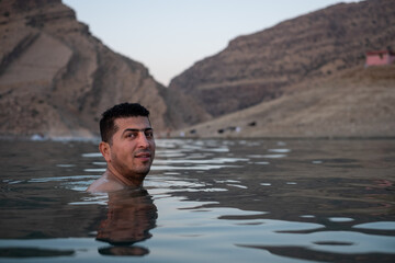 Kurdish man swims in Lake Dukan Iraq at dusk