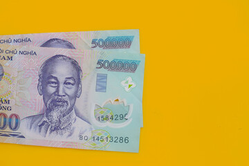 Vietnamese dong banknotes on yellow background.