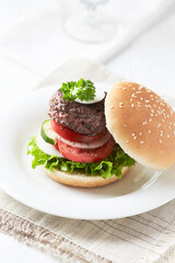 Tasty hamburger with tomatoes and onion. Bright wooden background.