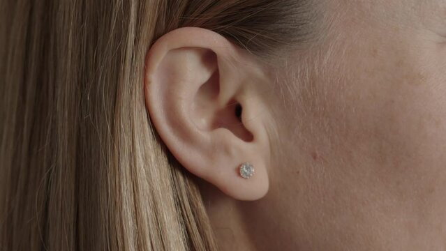 Detailed close-up of a woman's ear showcasing a small diamond stud earring. Perfect for jewelry, fashion, and beauty-related concepts.