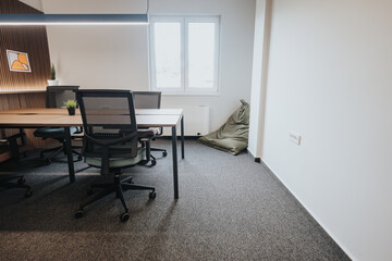 Stylish workspace featuring ergonomic chairs, large desk, and a relaxing bean bag in a cozy corner,...
