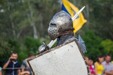 Battle of warriors tournament. Armed member of history club in knight armor demonstrating fighting...