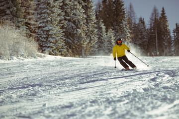 Young person in fashionable clothes is skiing towards the camera on a ski slope on a sunny day....