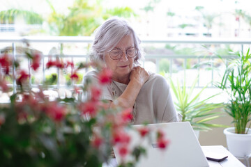 Stressed gray haired senior woman suffering from severe shoulder pain after studying or working on...