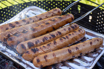 Bratwurst or hot dogs on grill. preparation of barbecue on sausage grill