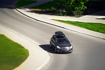 Urban Escape: Family Car with Rooftop Box Hits the Road