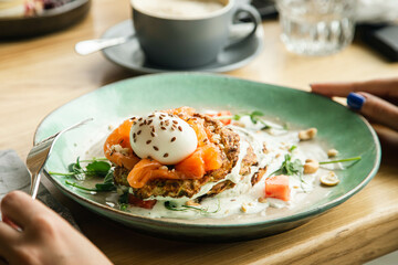 Vegetarian zucchini pancakes with poached egg, salmon and tomato, close up, healthy breakfast, top view.