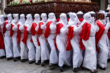 Penitents in White and Red March in Solemn Holy Week Observance