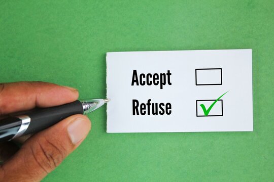 hand holding pen and white paper with two word options Accept or refuse? Refuse