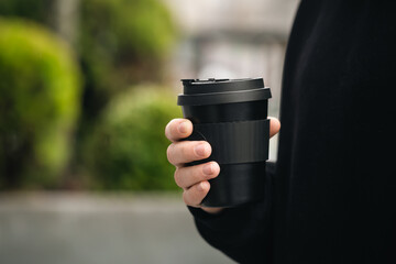Reusable stylish bamboo black cup in the hands of a man, close-up, Eco friendly sustainable handy...