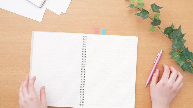 Girl opening a notebook. Class, classroom, desk, study, learning, homework, preparation, review, notes, business etc.　ノートを開く女の子。授業、教室、机、テーブル、学習、勉強、宿題、予習、復習、メモ、ビジネスなど