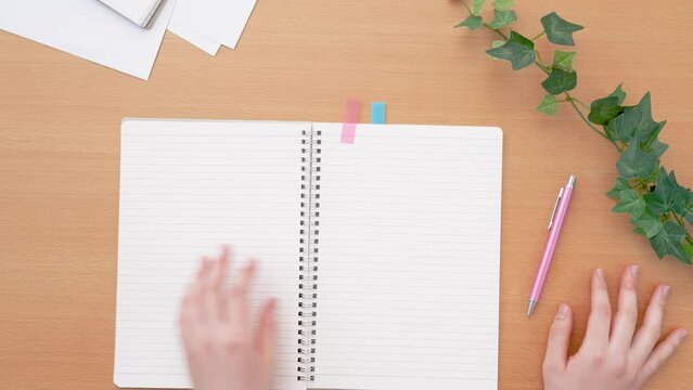 Girl opening a notebook. Class, classroom, desk, study, learning, homework, preparation, review, notes, business etc.　ノートを開く女の子。授業、教室、机、テーブル、学習、勉強、宿題、予習、復習、メモ、ビジネスなど