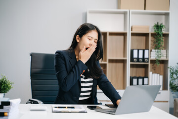 Overworked young Asian businesswoman office worker suffering from neck pain after had a long day at...