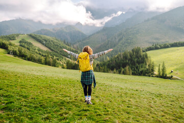 Woman tourist traveler walking on field, top of mountain in summer sunny day under sun light. Travel, nature concept.
