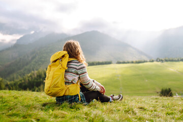 Woman tourist traveler walking on field, top of mountain in summer sunny day under sun light. Travel, nature concept.