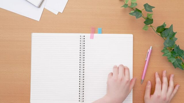 Girl opening a notebook. Class, classroom, desk, study, learning, homework, preparation, review, notes, business etc.　ノートを開く女の子。授業、教室、机、テーブル、学習、勉強、宿題、予習、復習、メモ、ビジネスなど