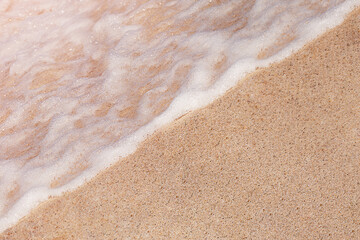 Sand beach with clear wave and sea foam, copy space