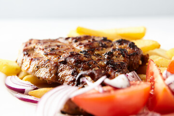 Grilled Steak with french fries and fresh tomatoes. White wooden background.