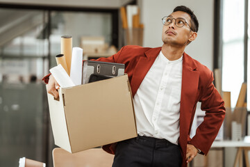 A middle-aged Asian businessman in a formal suit is working at his desk, preparing to resign after...