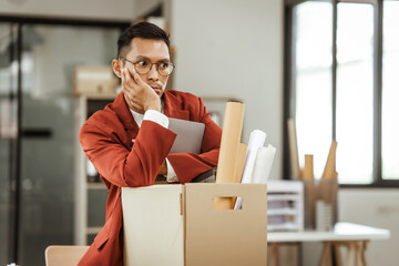 A middle-aged Asian businessman in a formal suit is working at his desk, preparing to resign after...