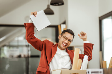 A middle-aged Asian businessman in a formal suit is working at his desk, preparing to resign after...