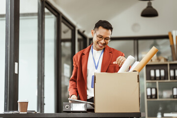 A middle-aged Asian businessman in a formal suit is working at his desk, preparing to resign after...