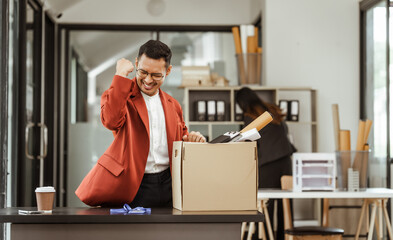 A middle-aged Asian businessman in a formal suit is working at his desk, preparing to resign after...