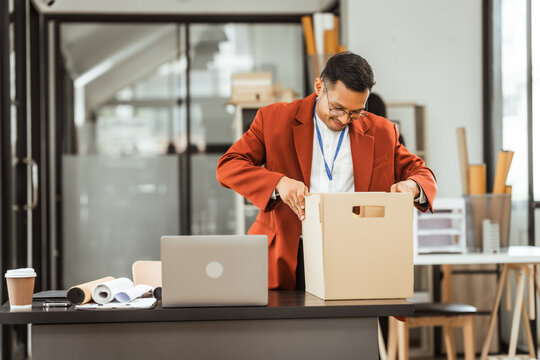 A middle-aged Asian businessman in a formal suit is working at his desk, preparing to resign after being laid off. He carefully reviews his resignation letter and finalizes the details.