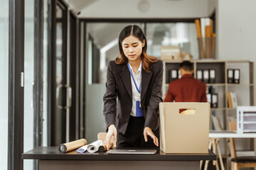 A young Asian businesswoman in a formal suit is working at her desk, preparing to resign after...