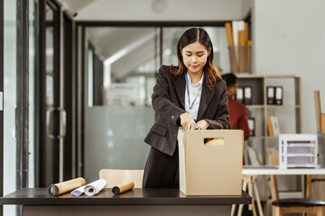 A young Asian businesswoman in a formal suit is working at her desk, preparing to resign after...