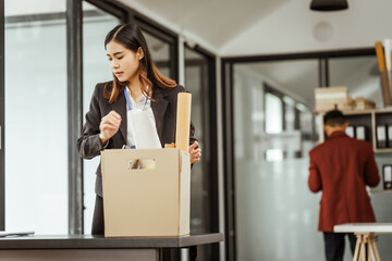 A young Asian businesswoman in a formal suit is working at her desk, preparing to resign after...