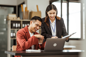 Middle-aged businessman and young Asian businesswoman work together at their desks, cooperation, collaboration, communication. teamwork, partnership, coordination to achieve mutual success.