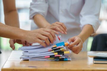 Close-up hand of Asian businesswoman and businessman arranging documents on their desk.