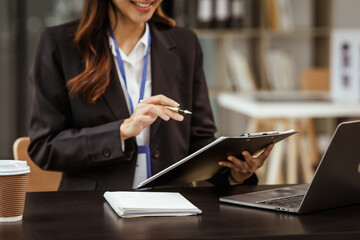 A young Asian businesswoman is seen diligently working at her desk. She's immersed in tasks ranging from recruitment and onboarding to performance management and diversity initiatives.