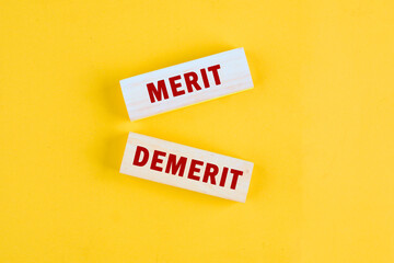 Merit and Demerit. fine concept. Text Demerit or merit symbol. a conceptual phrase on wooden blocks lying on a beautiful uniform tone
